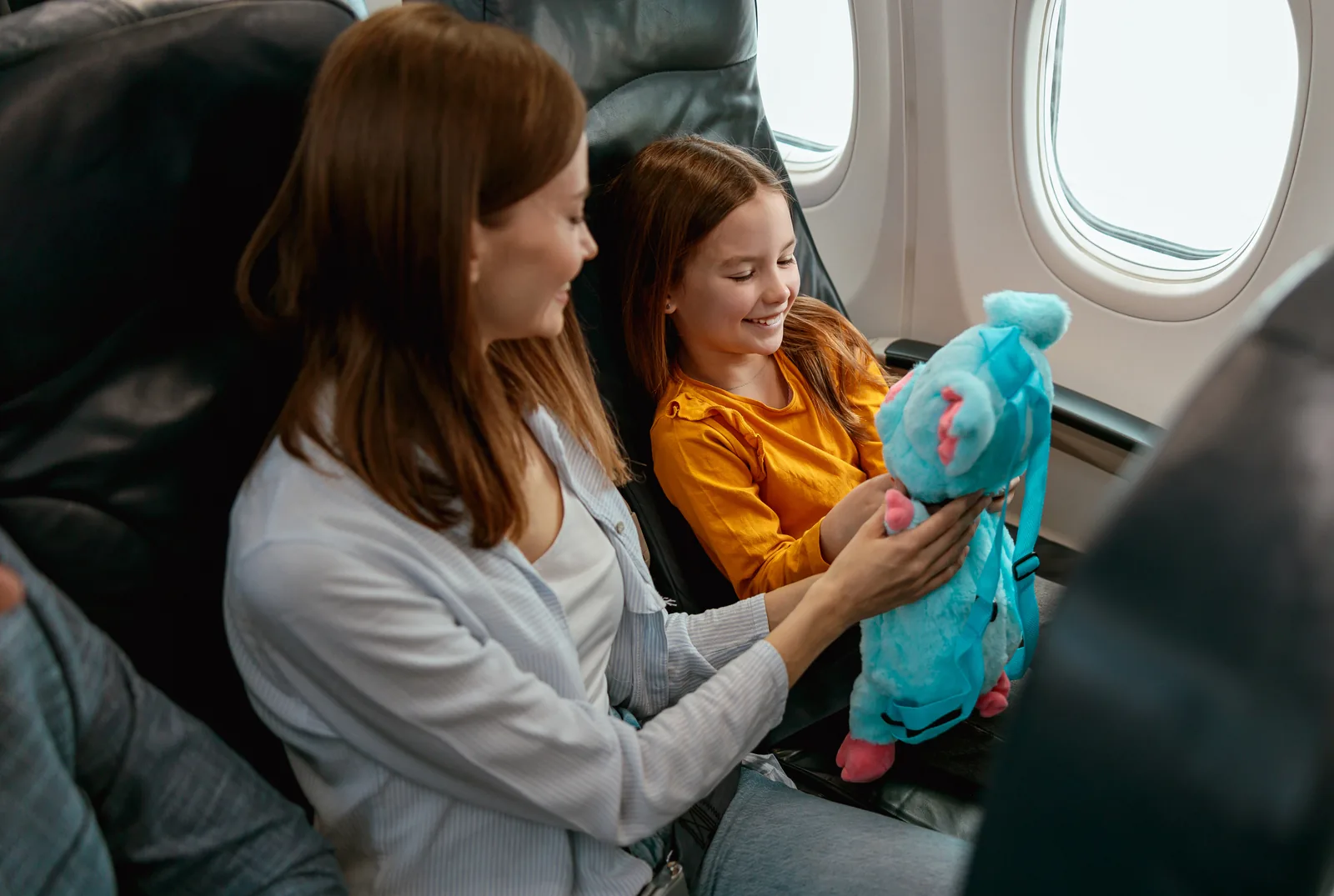 Child showing her parent a plush toy on a flight