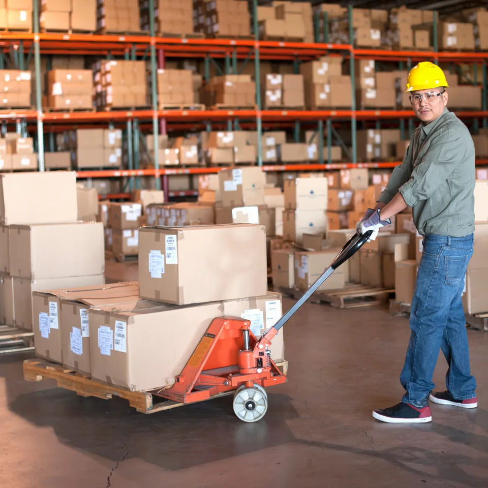 Warehouse worker moving cartons on a pallet jack