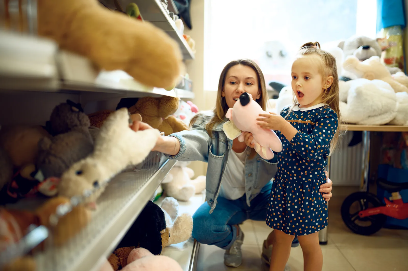 Parent and child choosing a soft toy from a shop shelf